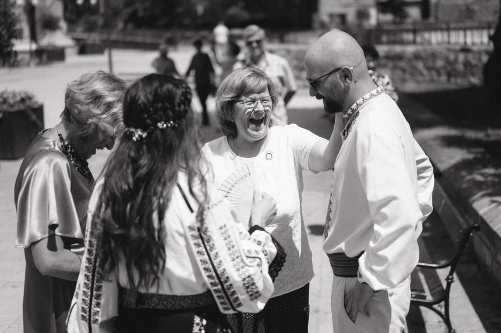 People in traditional dress sharing a joyful moment at an outdoor gathering.