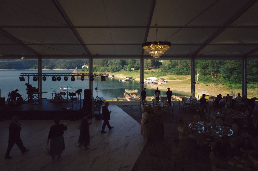 Evening wedding reception under a tent with scenic lake views at sunset.