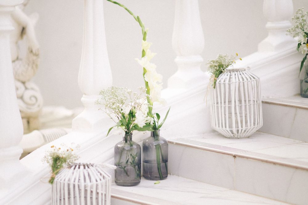 Minimalist white decor featuring delicate floral arrangements in glass vases.