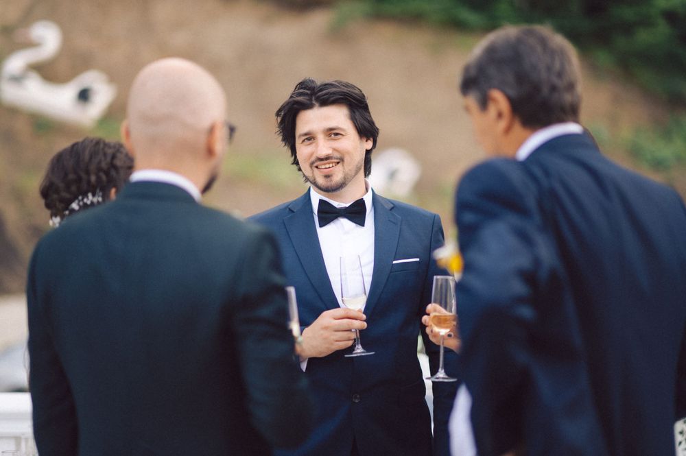 Guests in formal attire enjoying conversation at an elegant outdoor celebration.