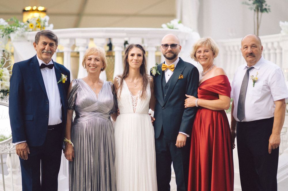 Wedding party in formal attire including metallic gowns and dark suits posing together at an elegant venue.