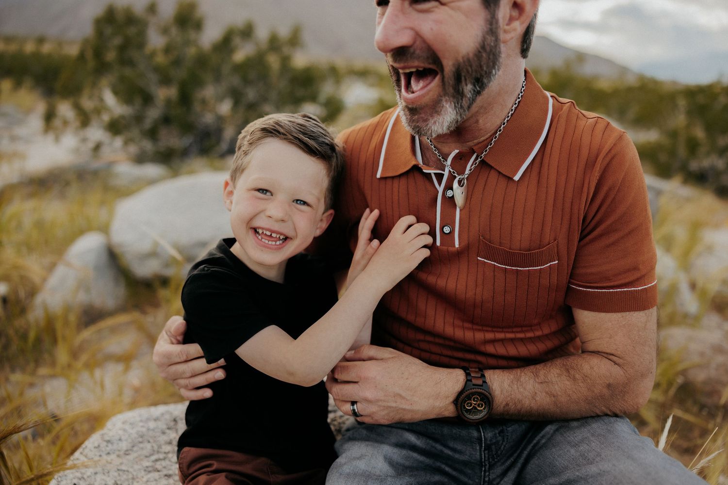 Joyful interaction captured on rocky desert terrain with mountains behind.