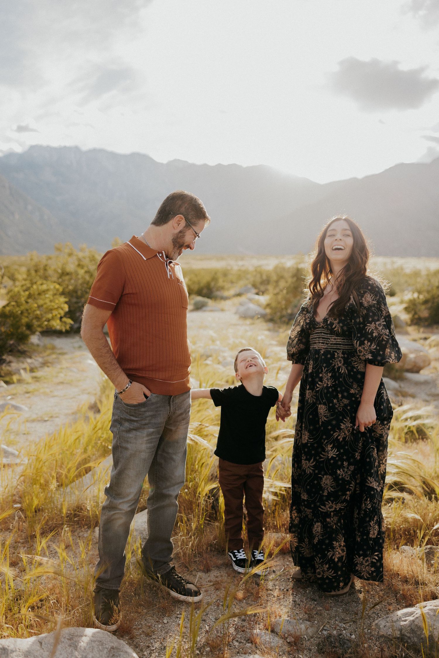Family sharing a joyful moment in desert landscape with mountain backdrop.