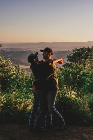 Silhouettes of grape pickers working in a vineyard at sunset against rolling hills in the distance.