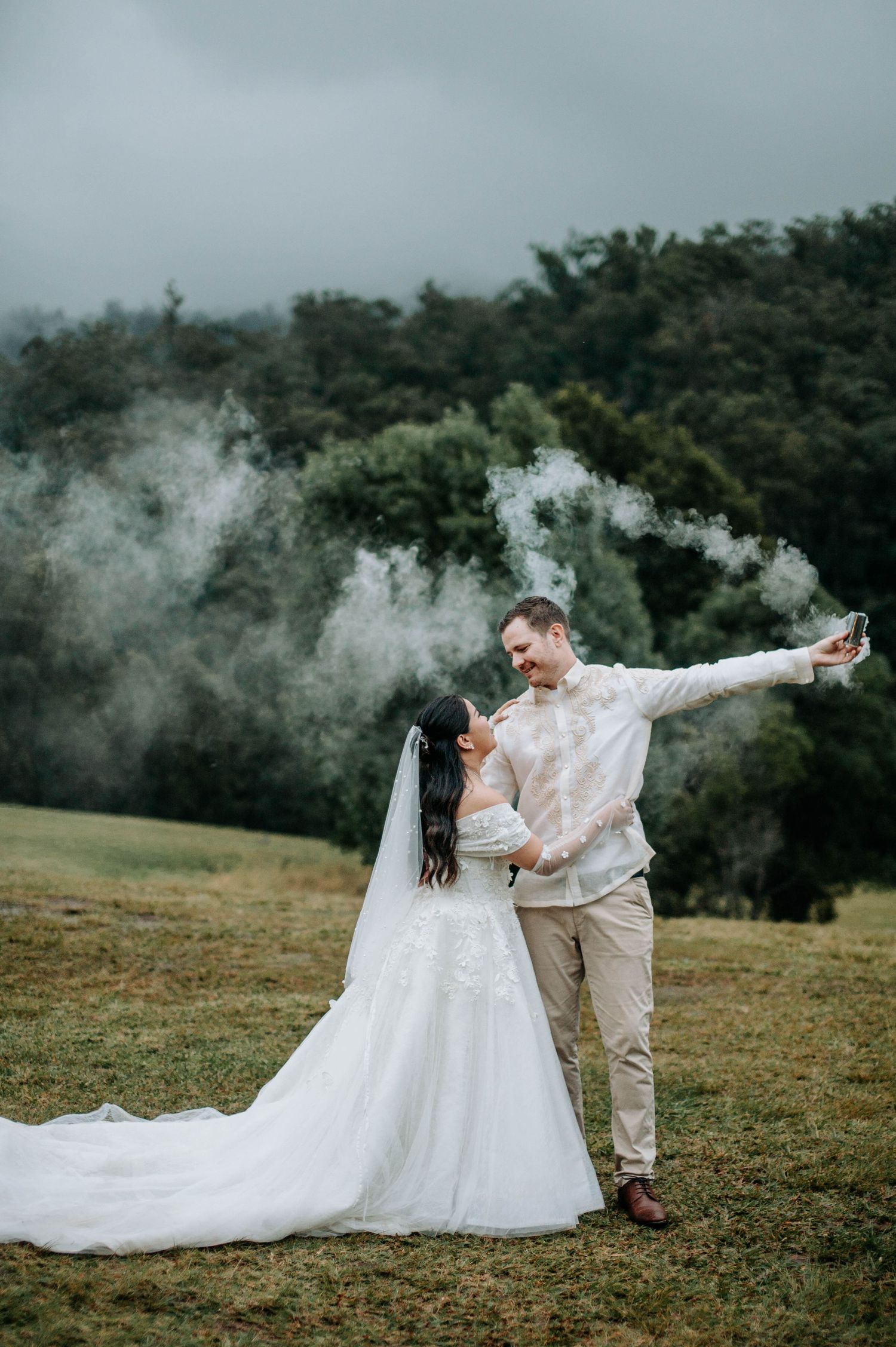 Romantic wedding photo with smoke effects on a misty hillside.
