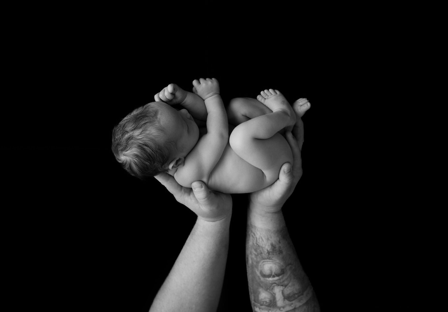 Nyfødtfotograf Sandnes - Svart/hvitt bilde av baby i pappas armer