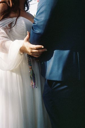 A couple embraces in formal attire against a dark background.