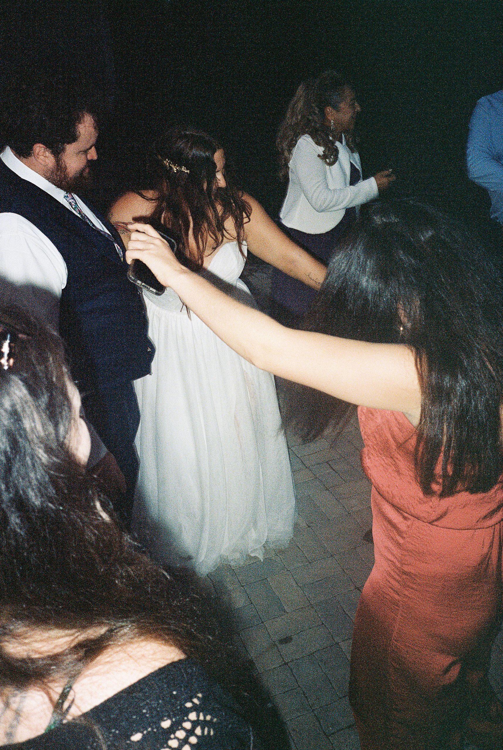 People dancing together in a dimly lit space during what appears to be a celebration.