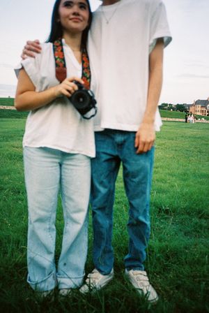 People standing together in casual jeans and t-shirts on grassy field.