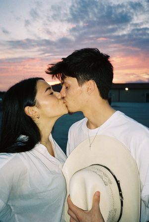 Romantic couple sharing tender moments with a cowboy hat during golden hour.