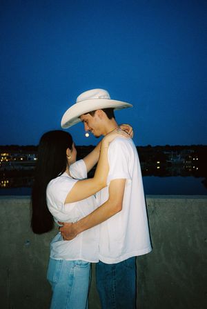 Silhouetted couple embracing under night sky while wearing cowboy hats.