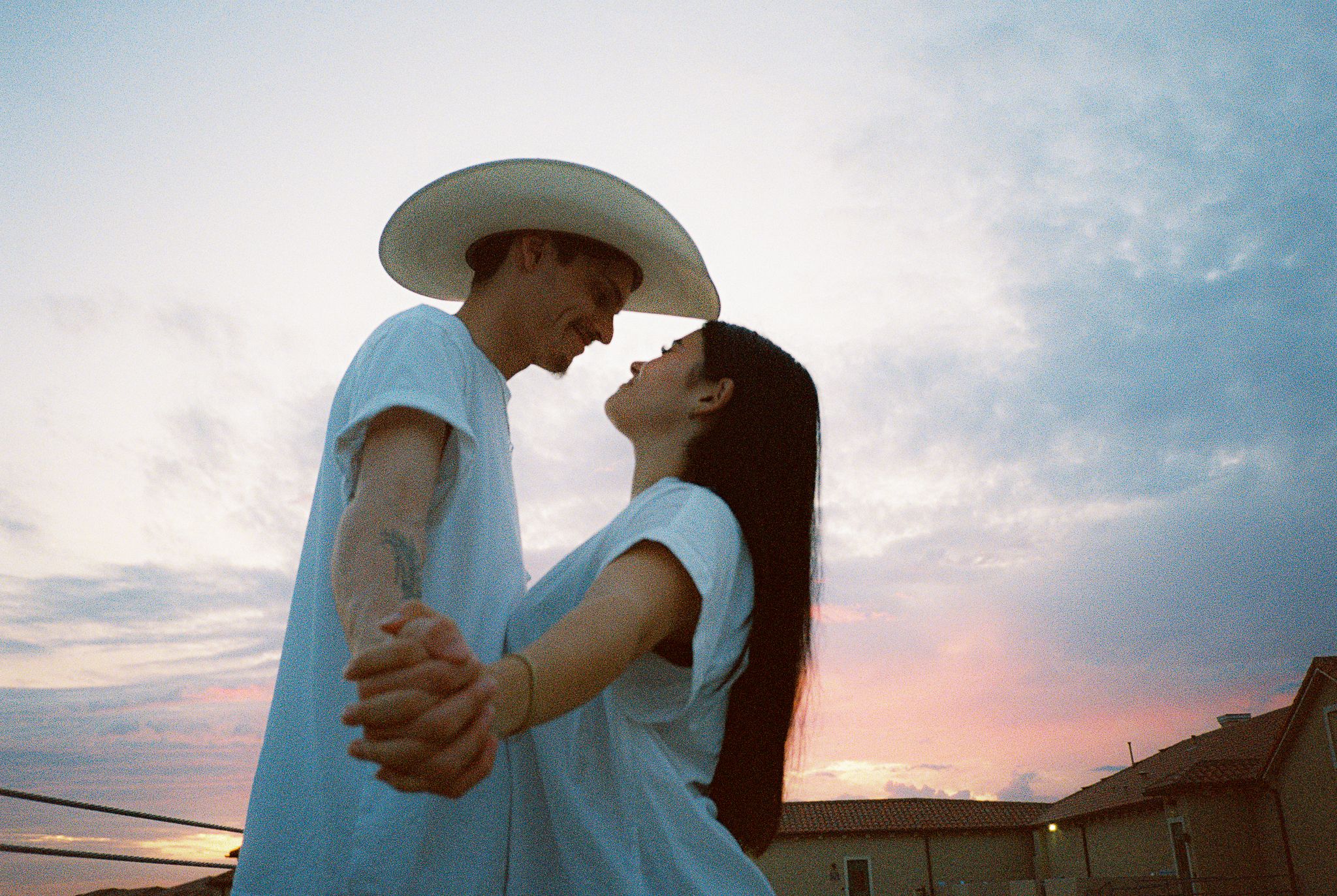 Couple in casual attire sharing romantic moments at dusk.
