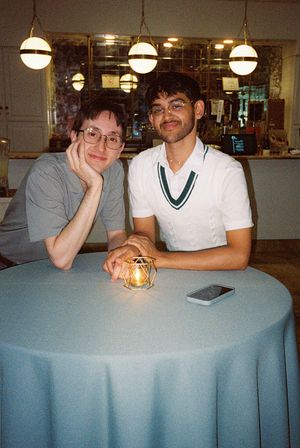 Friends gathered around a circular table with pendant lights hanging overhead.