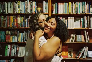 A couple shares an intimate moment while browsing books in a library setting.