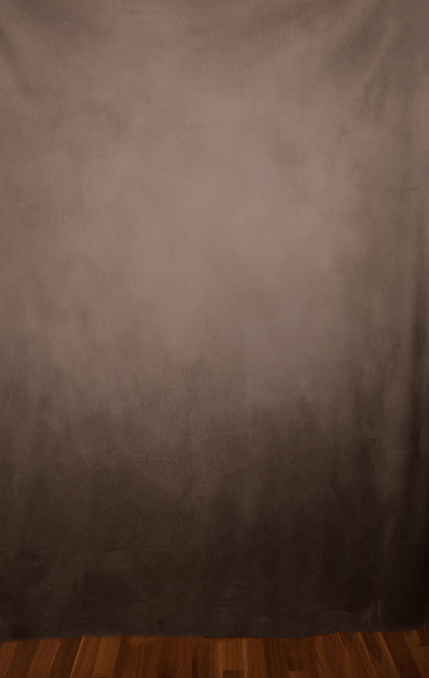 A mottled brown and gray photography backdrop with a gradient effect, displayed against a dark hardwood floor.