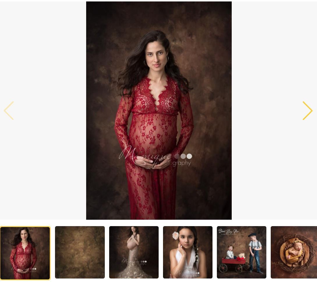 Pregnant woman in red lace maternity gown posing elegantly for a professional studio maternity photo session.