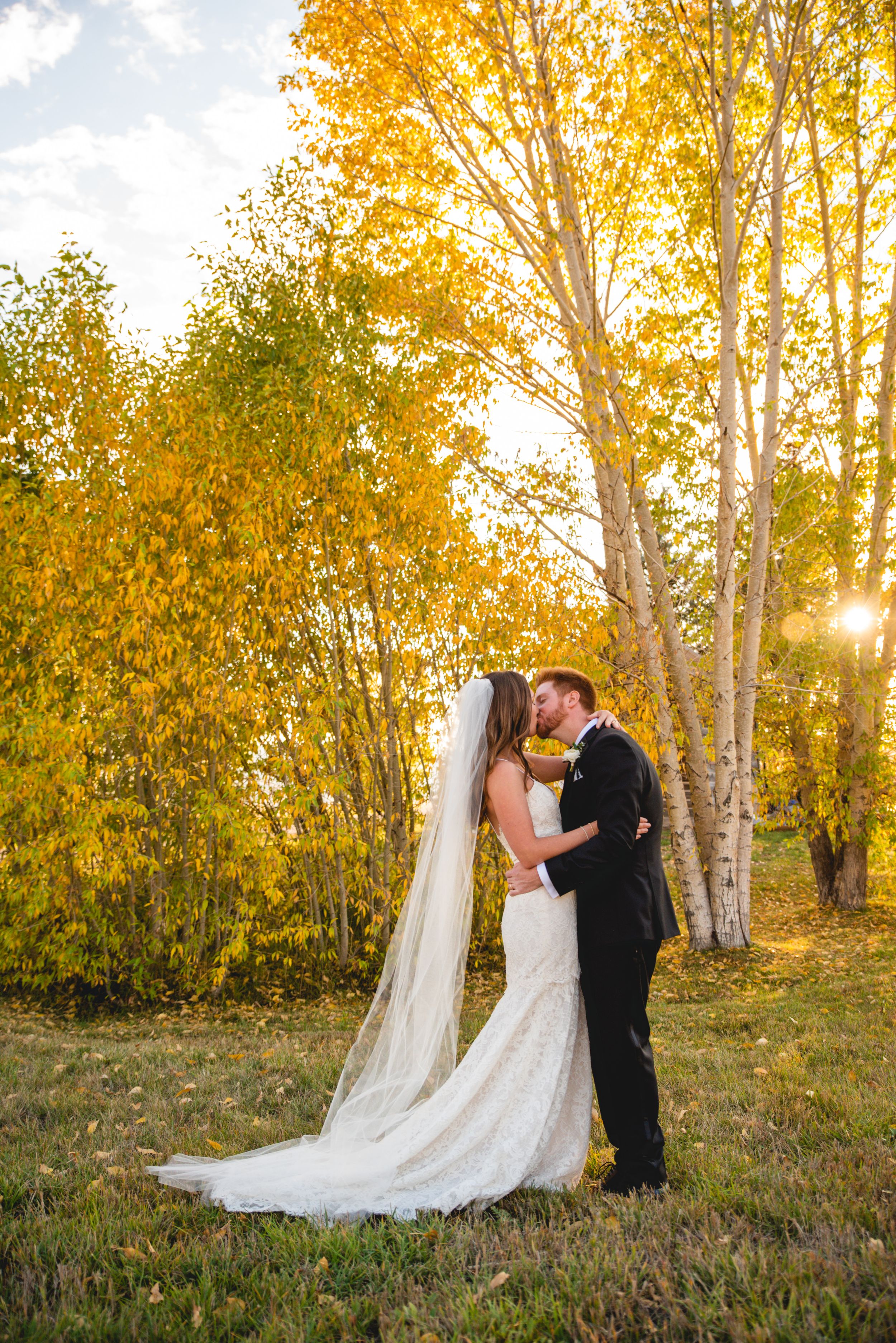 A romantic autumn wedding photo with golden aspen trees and sunlight filtering through the branches.