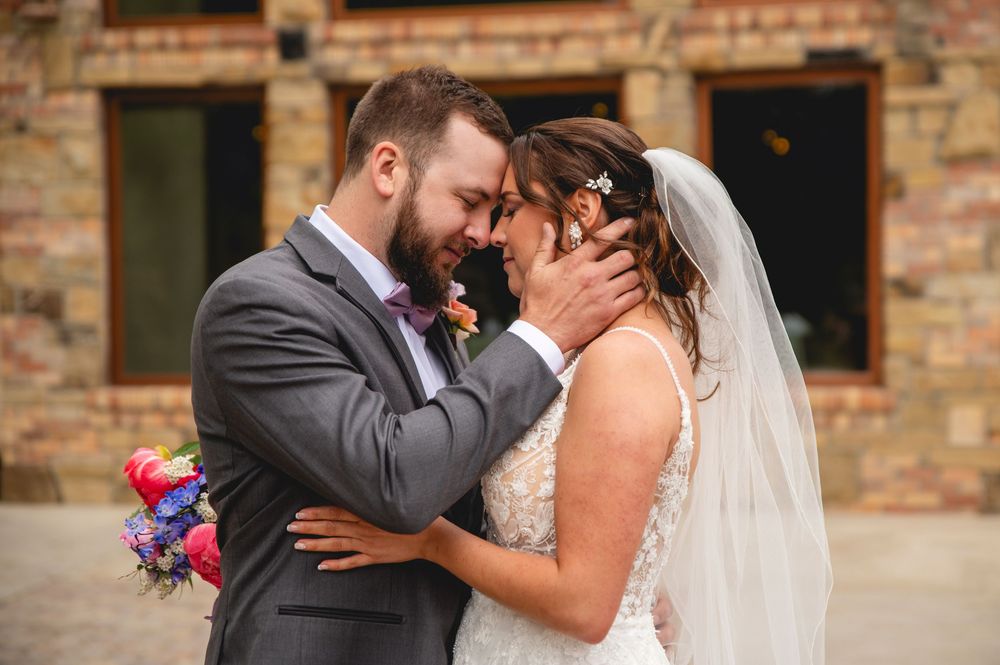 A romantic moment captured between newlyweds against a rustic brick wall backdrop at their wedding celebration.