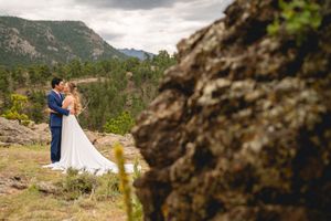Wedding couple shares intimate moment on mountain overlook with dramatic rocky landscape.