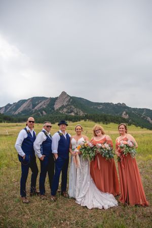 Wedding party in navy and rust colors poses with mountain backdrop in Boulder, Colorado.