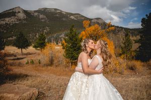 Romantic wedding portrait against backdrop of golden fall foliage and mountain scenery.