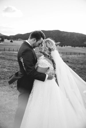 Romantic black and white portrait of couple with mountains and fence in background.