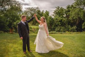 Joyful dancing couple celebrates on green lawn during wedding celebration.