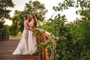 A romantic sunset wedding moment on a wooden bridge surrounded by lush greenery.