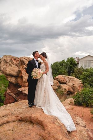 A romantic wedding couple poses along scenic red rock formations during their outdoor ceremony in nature.
