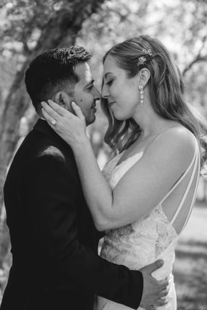 Intimate black and white portrait of tender wedding moment outdoors.