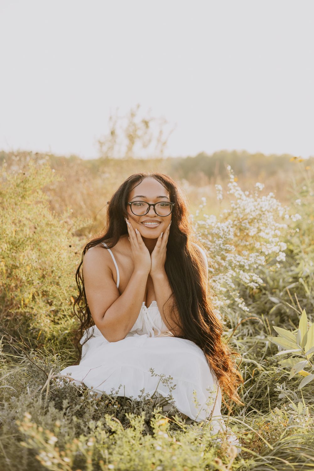 Woman in white dress laying in wildflower field during golden hour.