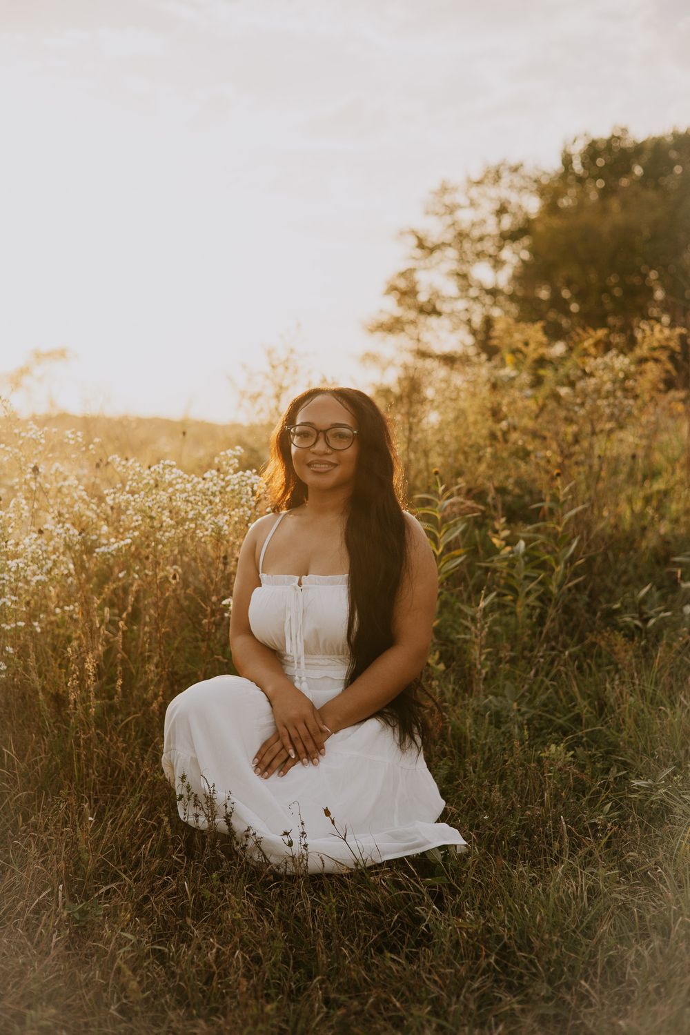 Casual outdoor portrait session in a meadow during golden hour with warm sunlight.
