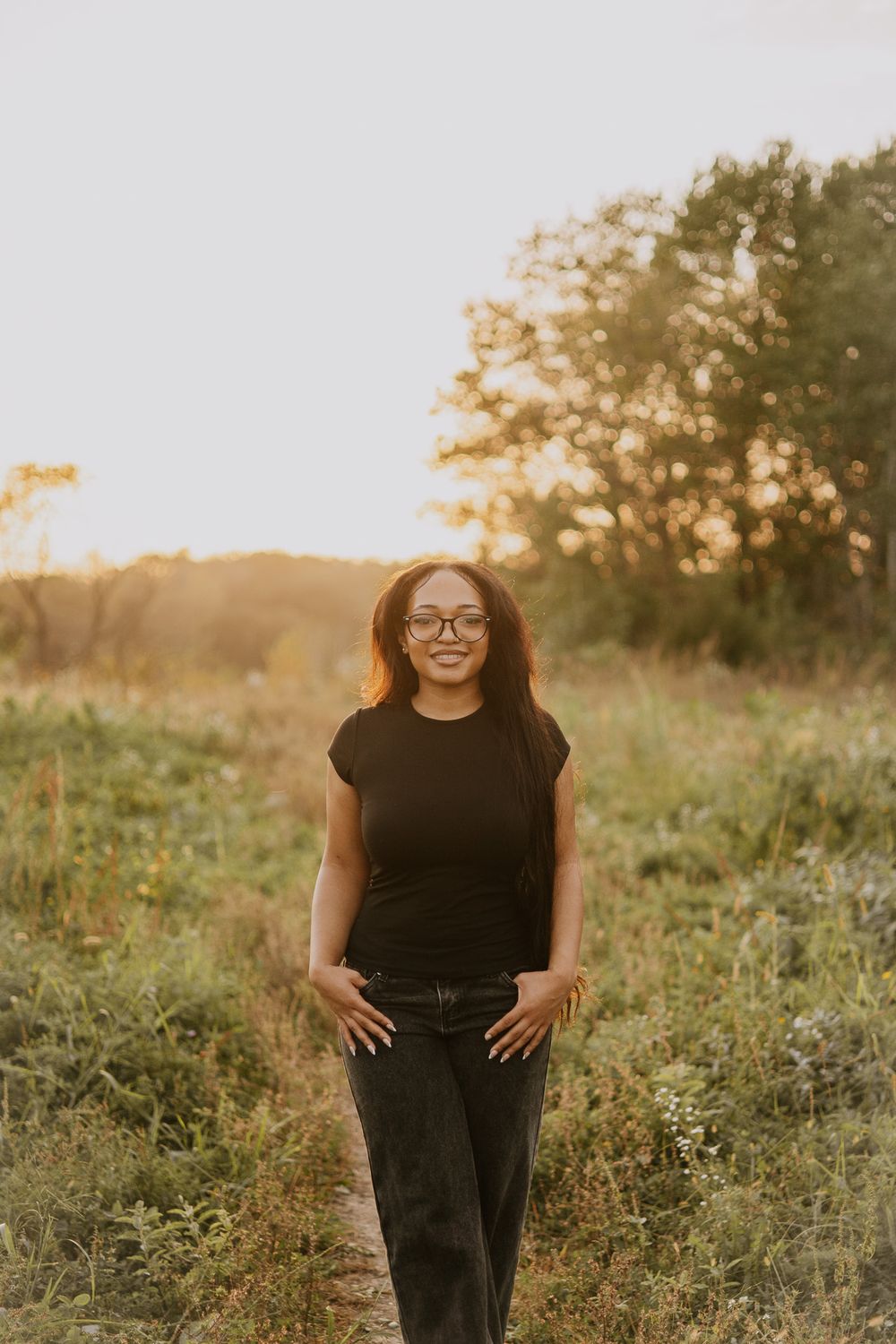 Natural outdoor portrait in black outfit among wildflowers at sunset.