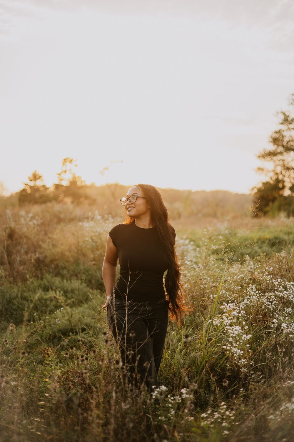 Artistic sunset portrait in a field of wild daisies with warm backlighting.