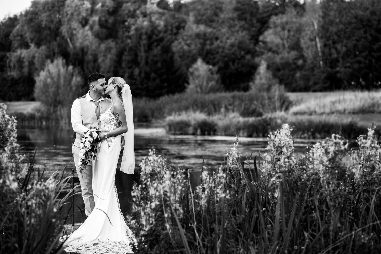 Golden hour wedding portraits by a scenic lake with natural sunlight streaming through.