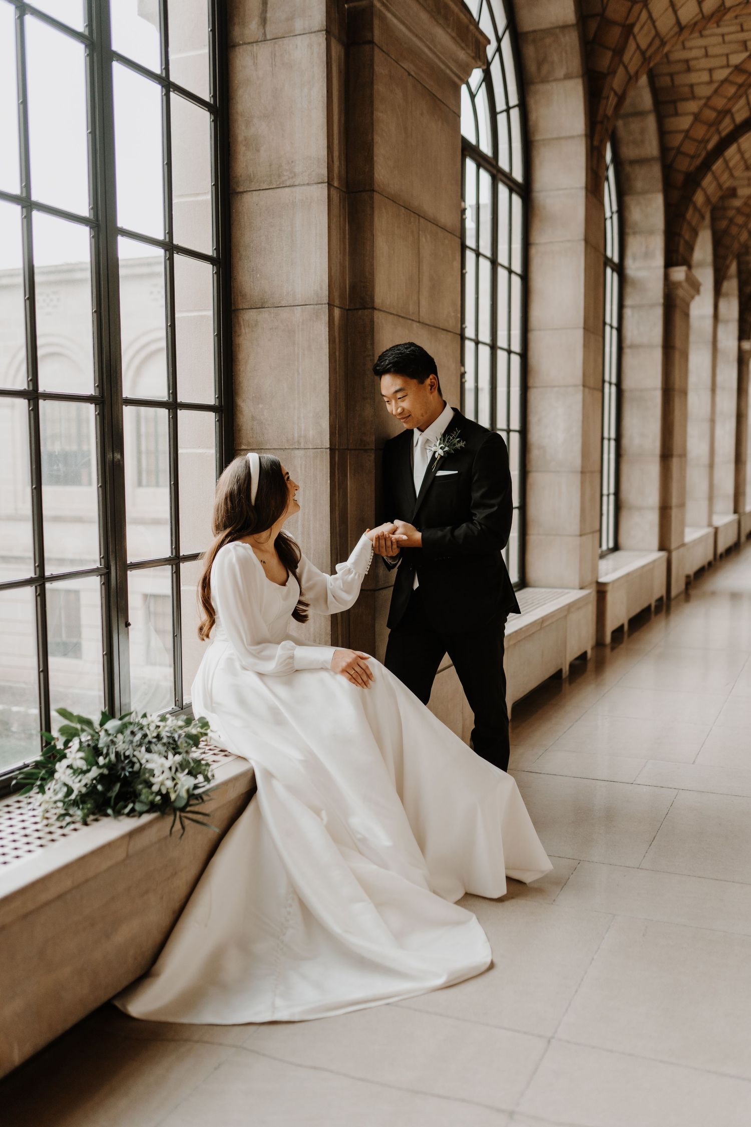 A series of indoor wedding photos showcasing a flowing white dress against large windows in an elegant hallway.
