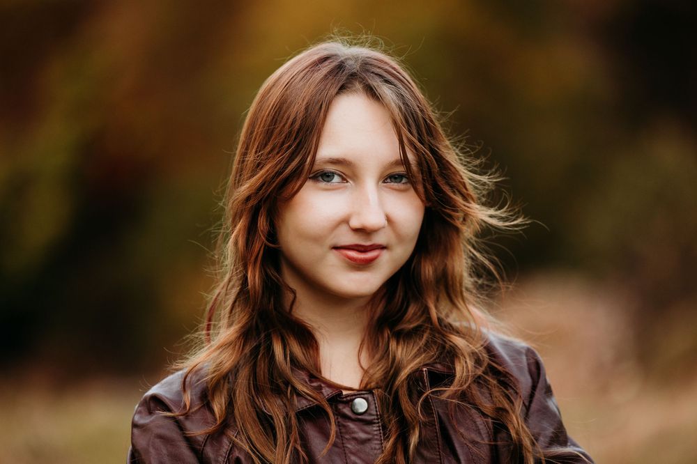 Portrait of young woman with flowing brown hair in autumn setting.