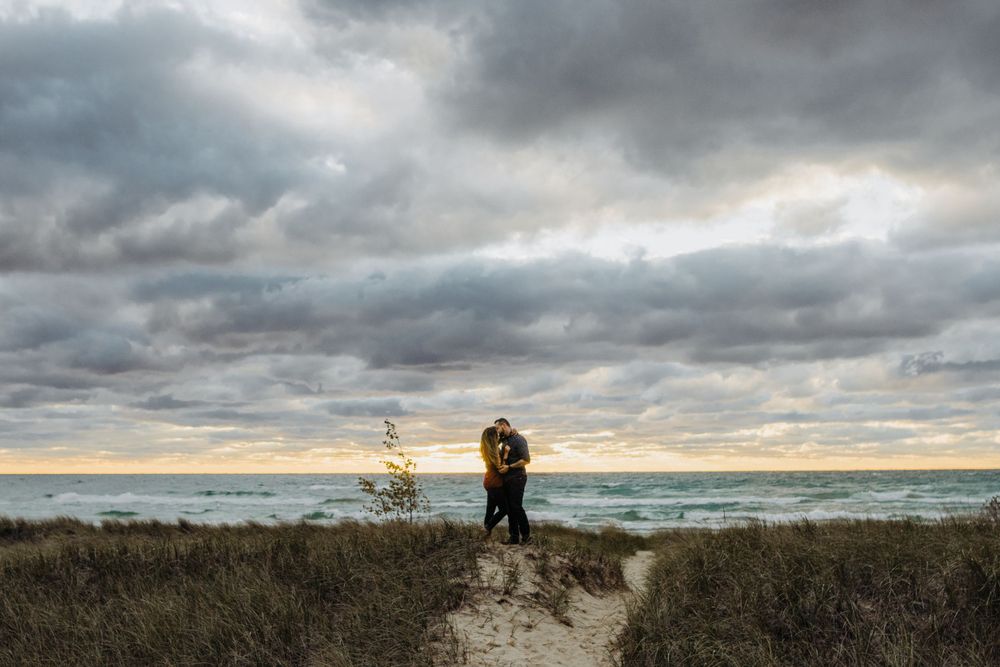 Couple embracing on coastal path against dramatic stormy sky.
