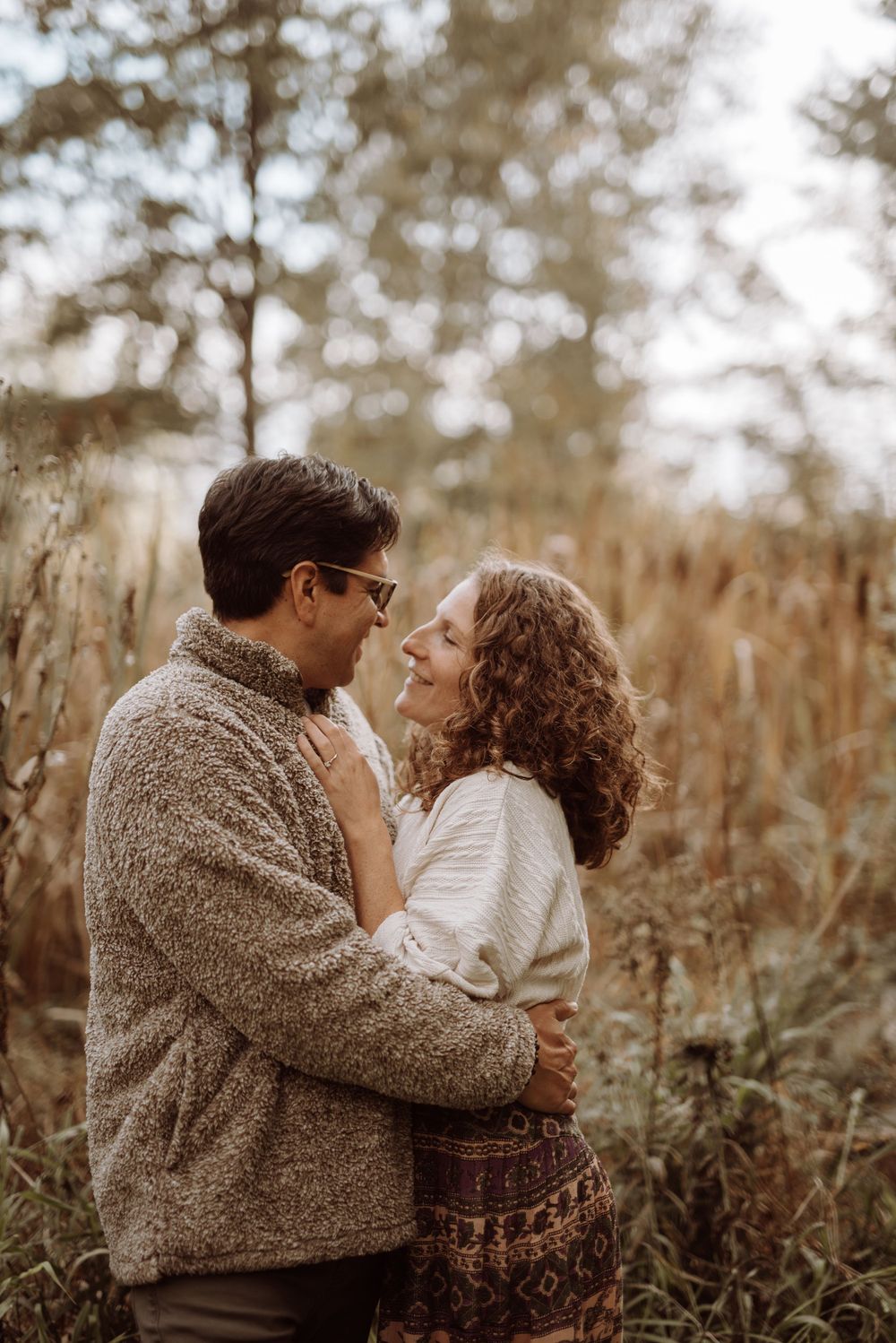 Romantic couple embracing in a rustic field surrounded by golden autumn foliage.