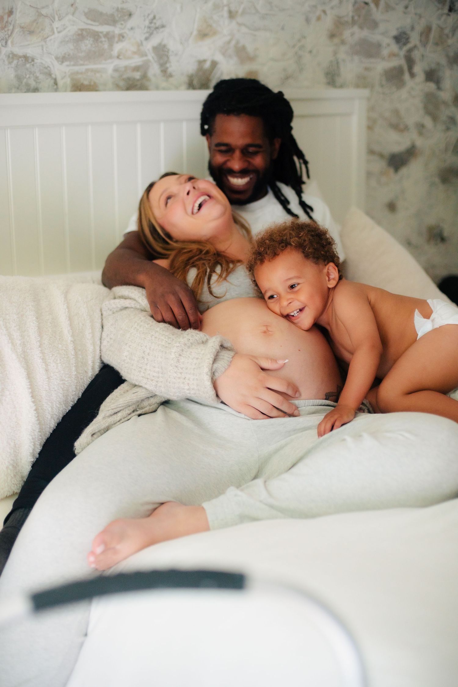 a mom, dad and toddler laughing in at in-home photography session in Massachusetts