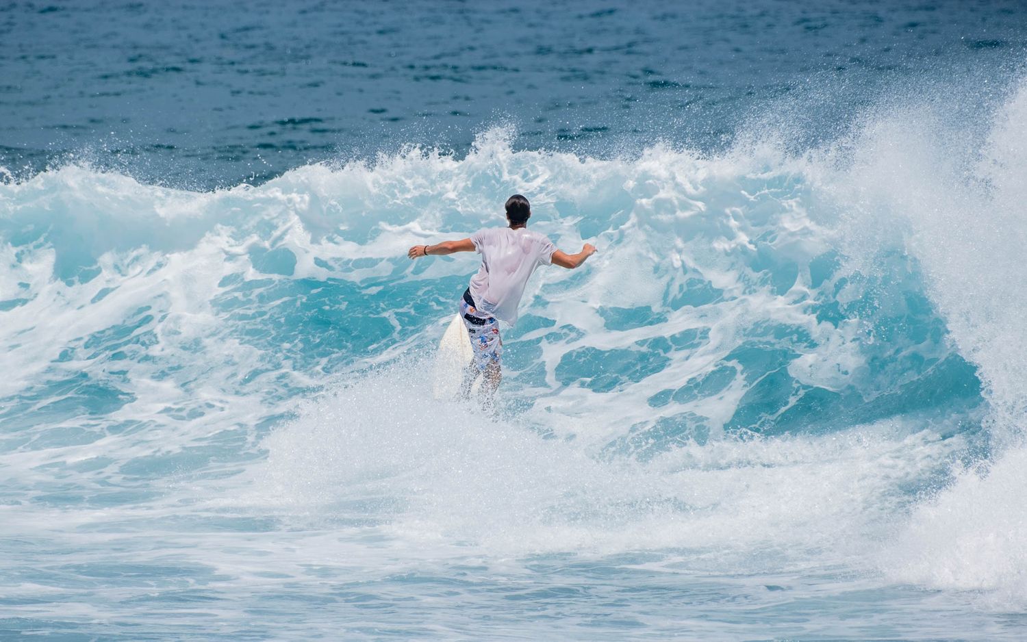 Surfer navigating through powerful white water on a breaking wave.