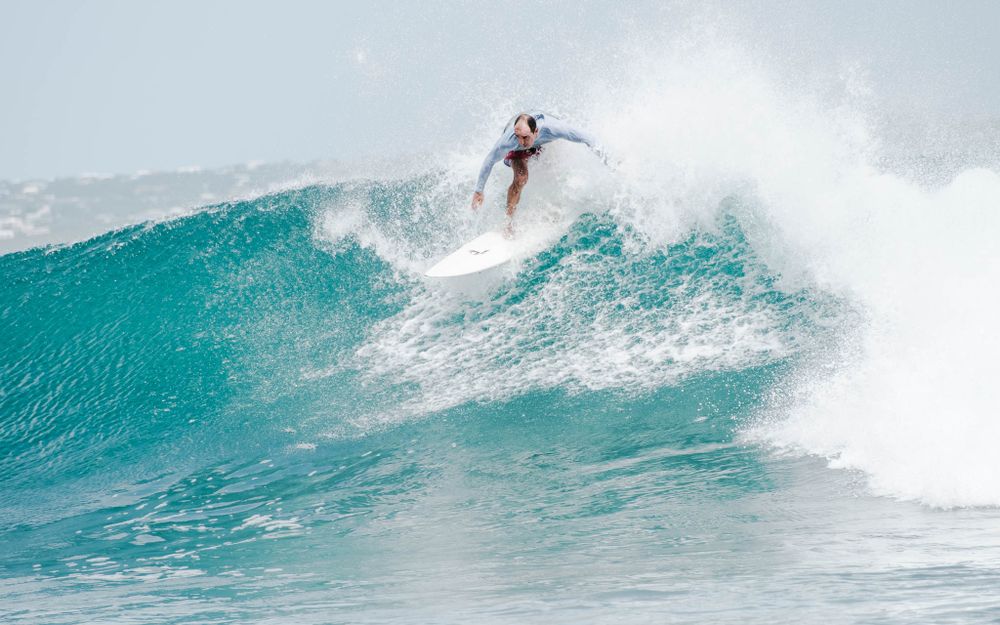Athletic surfer performs a powerful cutback maneuver on a pristine turquoise wave.