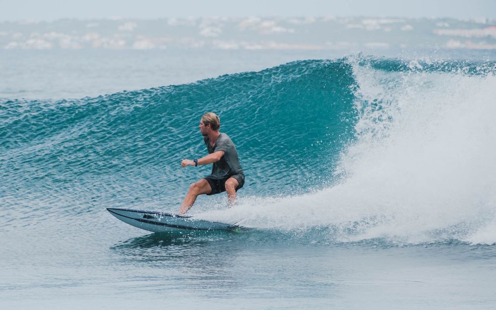 Surfer rides along a perfect turquoise wave during a session in tropical waters.