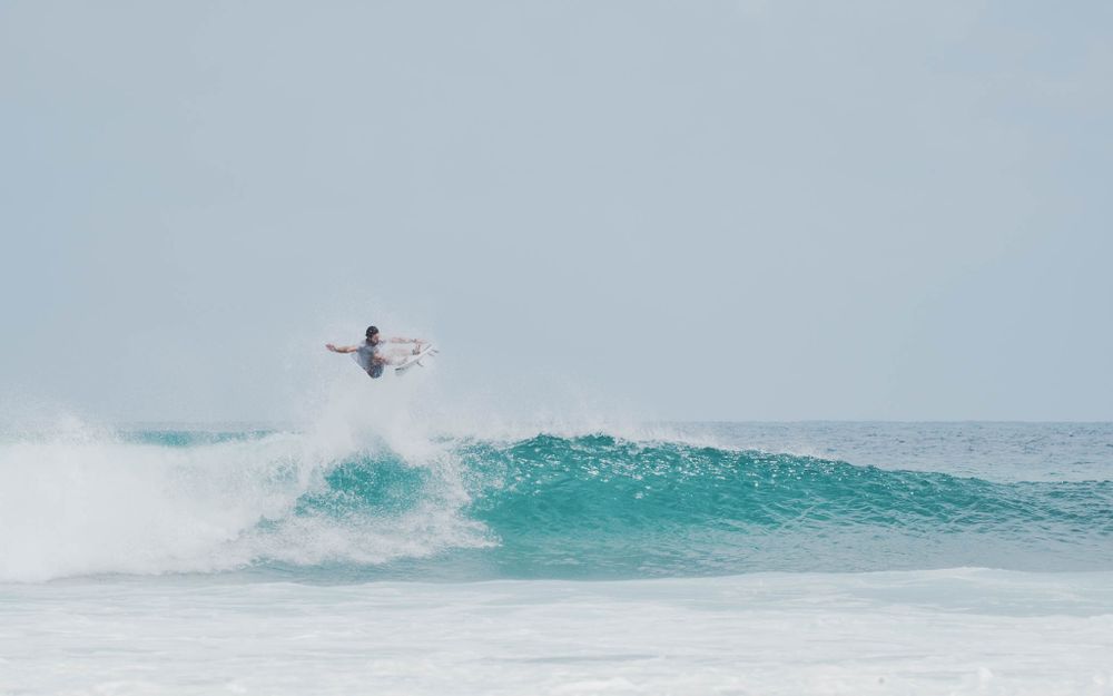 Surfer launches high into the air performing an aerial trick above ocean waves.