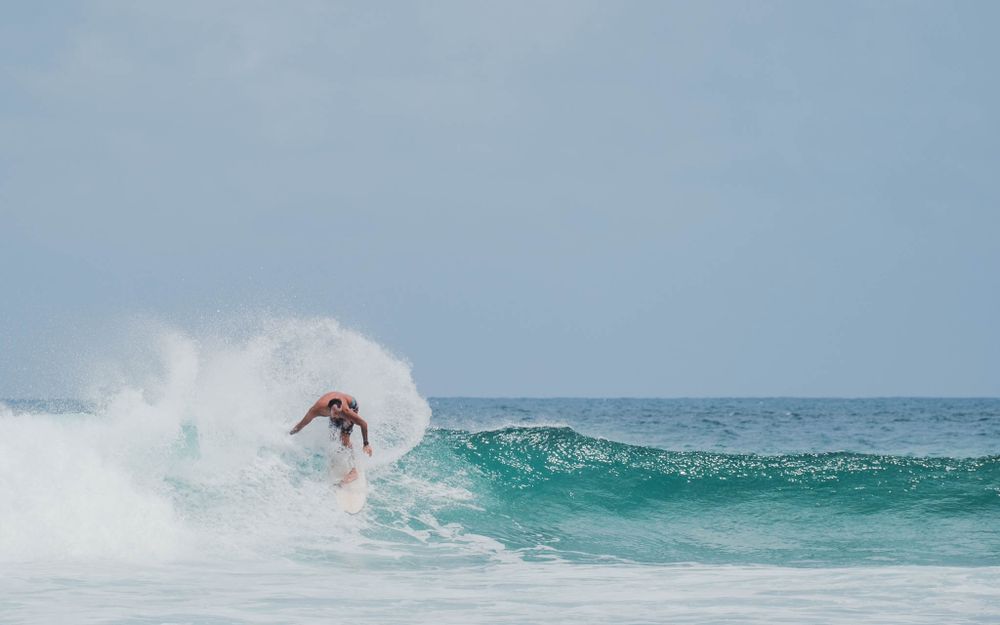 Dynamic shot of surfer performing aerial maneuver with spray against cloudy sky.