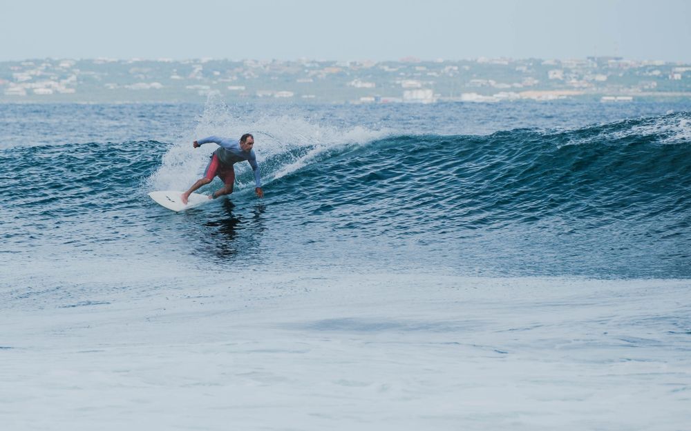 Surfer carves along the face of a clean blue ocean wave.