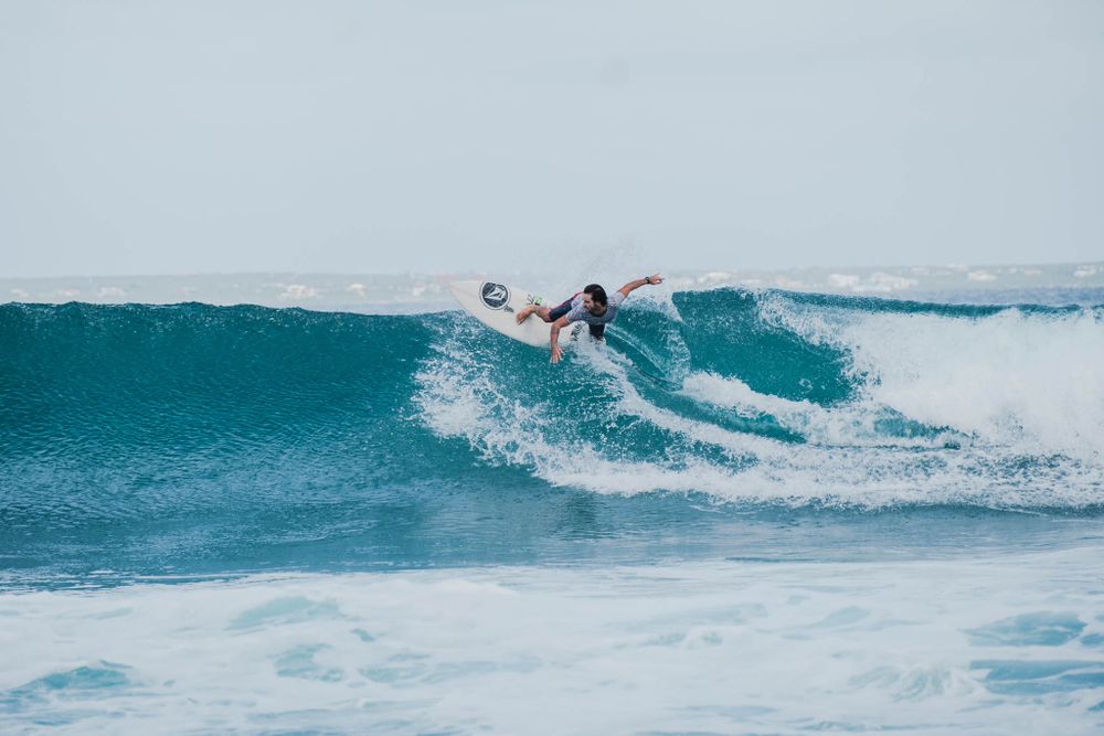 Surfer launches into a dramatic aerial maneuver off a breaking wave.