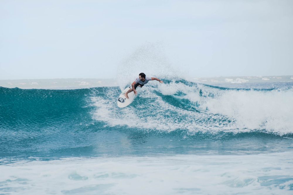 Surfer performs a powerful snap turn on the lip of a blue ocean wave.