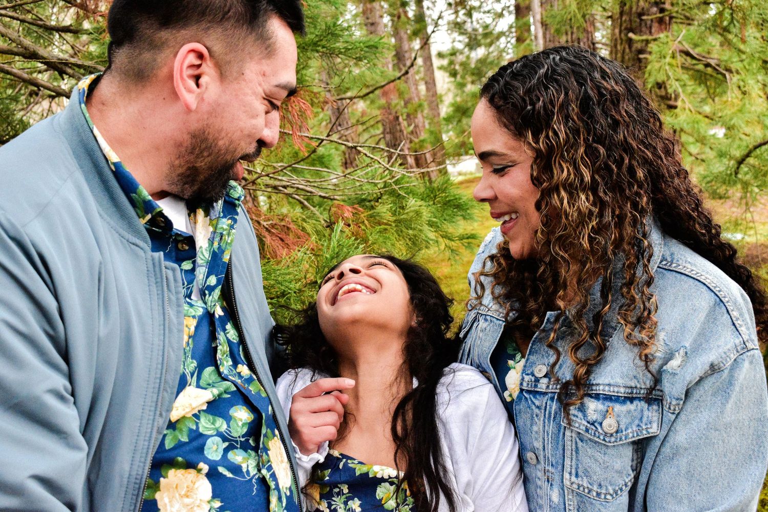A joyful family shares a candid moment of laughter together in a lush forest setting. Seattle family photography.