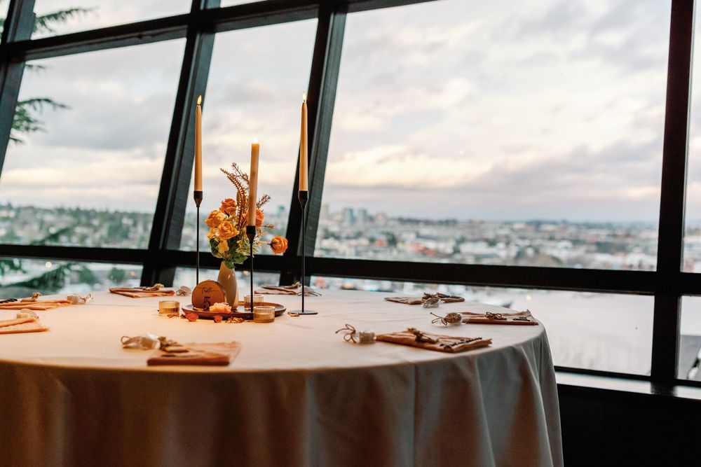 Romantic wedding sweetheart table with candles and flowers overlooking a stunning city skyline view.